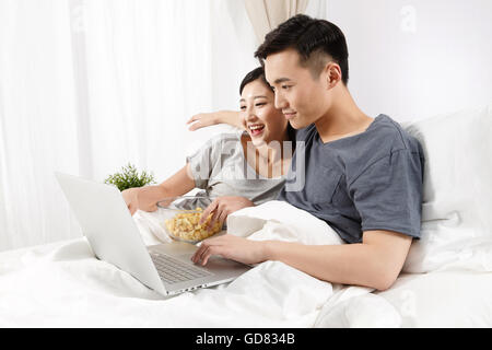 Young couple sitting on the bed to see the computer Stock Photo