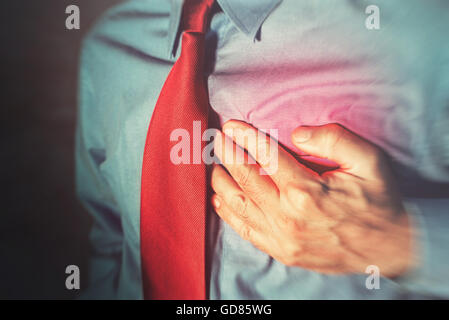 Unrecognizable businessman having chest pain and heart attack, hand holding the painful spot. Stock Photo