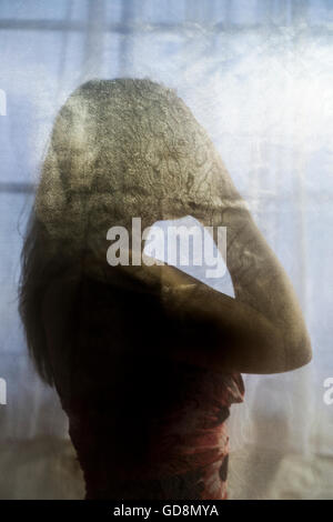 Hiding nude woman in silhouette behind a sheer white lace curtain Stock