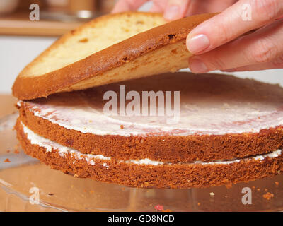 Stacking cake layers. Making torte with buttercream filling and grated chocolate topping. Series. Stock Photo
