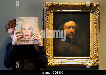 Gallery assistant Harris Brine stands next to a self portrait by Rembrandt, painted in 1657, which features in the new exhibition Facing the World: Self Portrait Rembrandt to Al Weiwei at the Scottish National Portrait Gallery in Edinburgh. Stock Photo