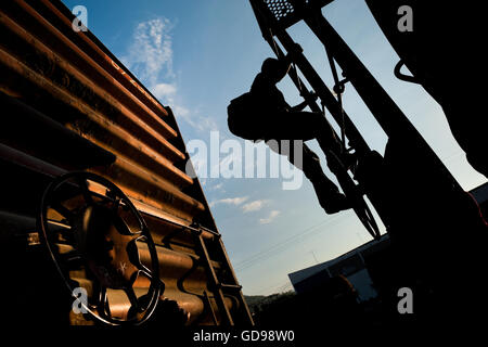 A young immigrant, heading from El Salvador to the United States, climbs up the cargo train in Arriaga, Mexico. Stock Photo
