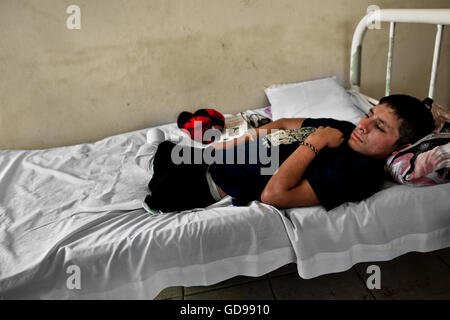 A 16-year-old Honduran immigrant, having both his legs amputated by a train, lies on the bed in a shelter in Tapachula, Mexico. Stock Photo