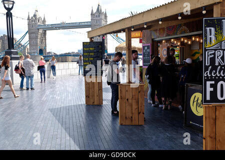 A food stall on the walkway on the south bank of the Thames London Bridge is in the background. Stock Photo