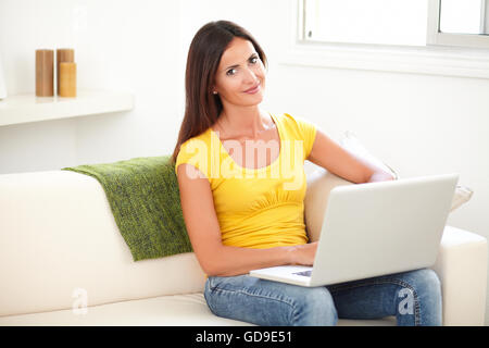 Attractive student looking at the camera while using a laptop at indoors Stock Photo