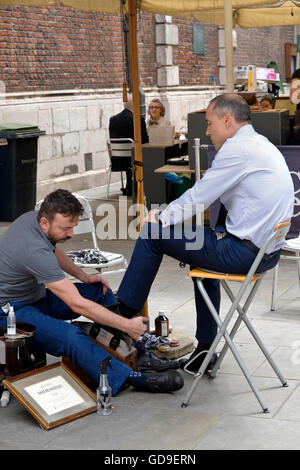 A businessman gets his shoes shined by a street shoe shine vendor in the City of London Stock Photo