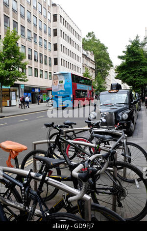 A row of bicycles parked and locked up on bike racks on the street in the City of London Stock Photo