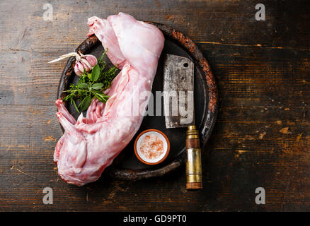 Raw whole rabbit and meat cleaver on dark wooden background Stock Photo