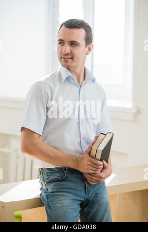 Portrait of young man holding books, looking sideways Stock Photo