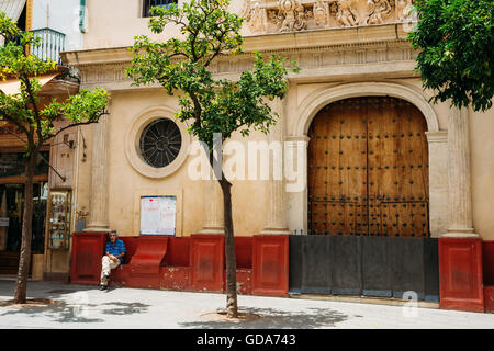 Seville, Spain - June 24, 2015: Man sitting near entrance to church at hospital San Juan de Dios on plaza del salvador in Sevill Stock Photo