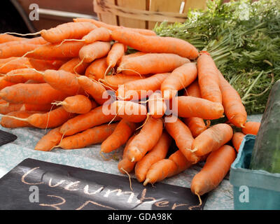 A pile of fresh carrots on a table top at a countryside farmer's market. Stock Photo