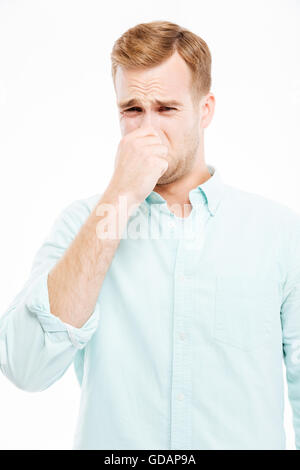 Sad unhappy young businessman closed his nose by hand and feeling bad smell over white background Stock Photo