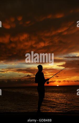 A Cuban fisherman fishing during a dramatic sunset. Stock Photo