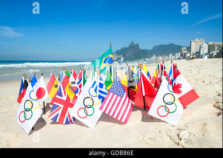 RIO DE JANEIRO - MARCH 20, 2015: Olympic flags fly together with an array of Brazil and international flags on the sand. Stock Photo