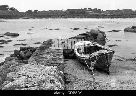 Abandoned boat by an old stone jetty, Porth Hellick, St. Mary's, Isle of Scilly, UK.  Black and white version Stock Photo