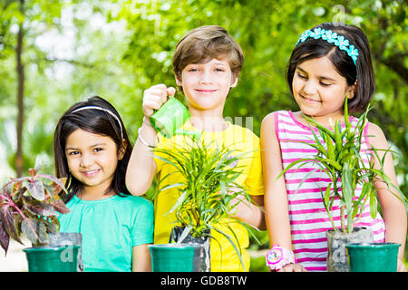 3 indians Kids friends park Watering Can Pouring Water Stock Photo