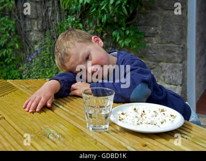 two year old boy sitting at a table Stock Photo