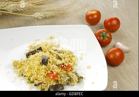 Couscous whit vegetables in a white ceramic plate with wooden background Stock Photo