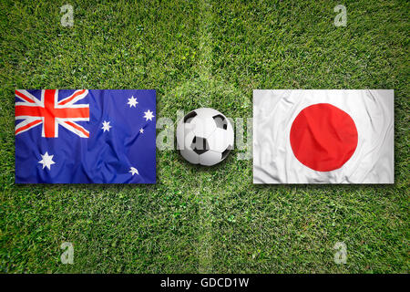 Australia vs. Japan flags on green soccer field Stock Photo