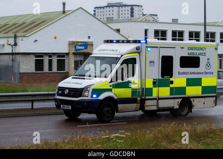 A Scottish Ambulance Service emergency ambulance responding to an emergency 999 call along on a wet Kingsway West Dual Carriageway in Dundee, Scotland Stock Photo