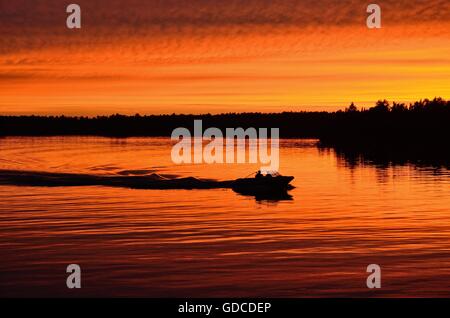 Boat Motoring After Sunset on a Calm Lake Stock Photo