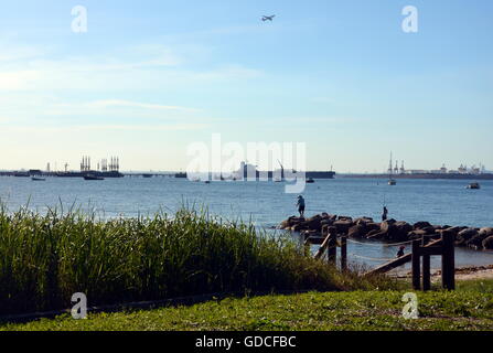 Sydney, Australia - Apr 21, 2014. People fishing on the breakwall. Tankers and Botany bay's industrial area in the background. Stock Photo