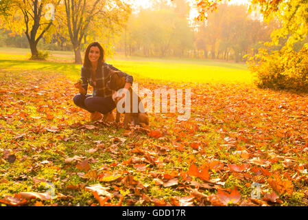 Beautiful young woman playing with her Dog in the Park in the autumn. Stock Photo