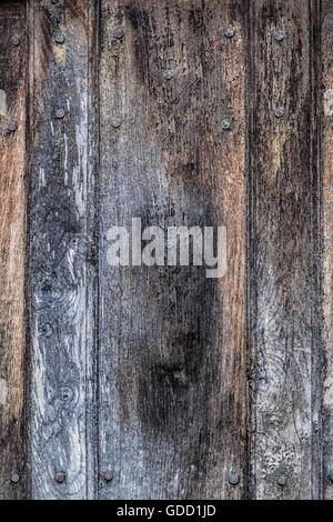 Panel of old faded and flaking wood studded with rusty nails for background texture Stock Photo