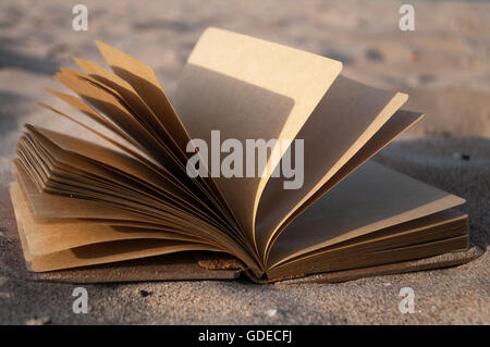 open the notebook in the sand closeup Stock Photo