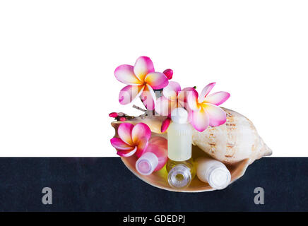 Isolated mini set of bubble bath and shower gel in sea conch shell with pink flower plumeria or frangipani on white background w Stock Photo