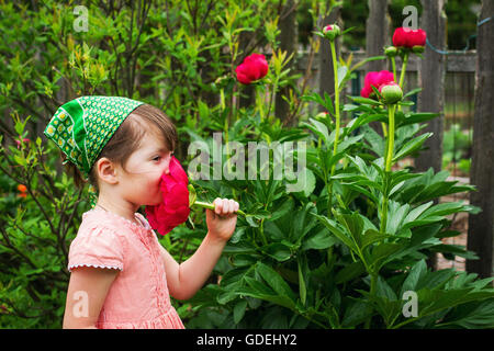 Girl smelling peony flower in garden Stock Photo