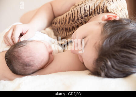 Mother lying on bed with newborn baby boy Stock Photo