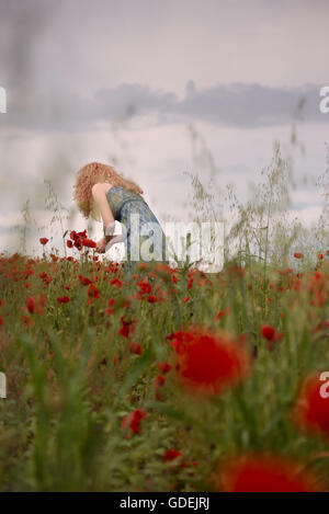Woman picking poppy flowers in field