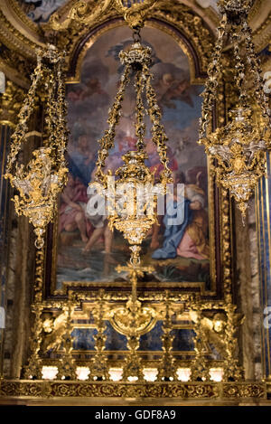 Igreja de Sao Roque Chapel St John Baptist Altarpiece Gold Lantern Lisbon Portugal | LISBON, Portugal — An elaborate gold-and-silver lantern hangs before the altarpiece of the Chapel of St John the Baptist (Capela de São João Baptista) at the Igreja de São Roque, the blue-veined columns flanking the scene among the chapel's inlays of lapis lazuli, agate, amethyst, and porphyry. The chapel was built entirely in Rome between about 1742 and 1747 by Nicola Salvi — designer of the Trevi Fountain — and Luigi Vanvitelli, blessed by Pope Benedict XIV, then dismantled and shipped to Lisbon on three ves Stock Photo