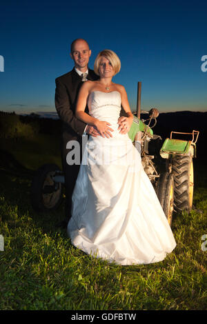 Happy bride and groom standing in a field during twilight Stock Photo