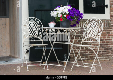 terrace with two old metal chairs and primroses on the table Stock Photo