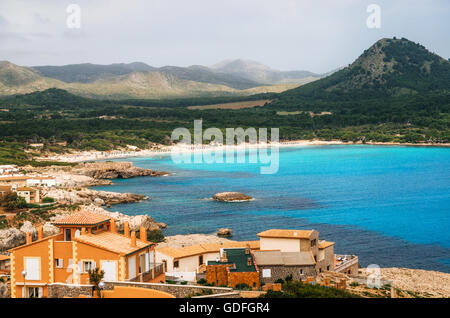 View of the Cala Agulla Beach in Mallorca island, Spain. Beautiful landscape with Es Pelats village, whitesand beach, green hill Stock Photo
