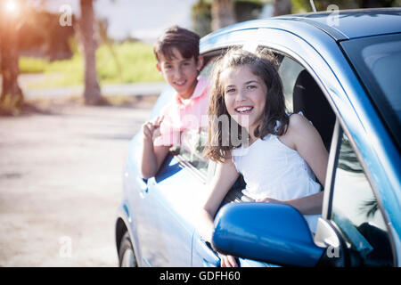 Funny and cute boy and girl in the car on nature background Stock Photo