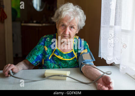 Elderly woman pensioner measures the blood pressure itself. Stock Photo