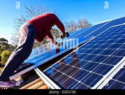 Fitting solar panels to roof of house Stock Photo
