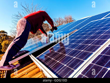 Workman installing solar panels on house roof Stock Photo