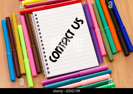 Contact us written on notebook over wooden background Stock Photo