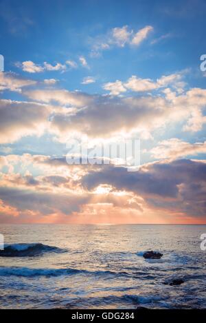 Beautiful sunrise over the sea. Sun beams break through the clouds.