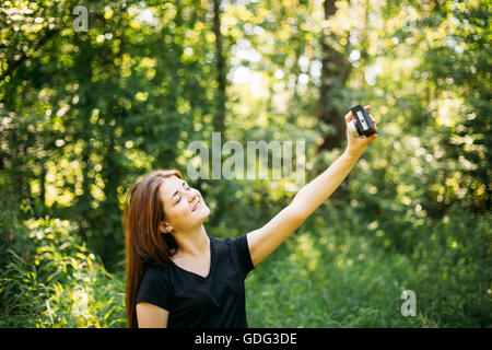 Happy Red-haired Caucasian Girl Young Woman Photographer Taking Selfie And Pictures The Old Retro Vintage Film Camera In Summer Stock Photo