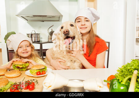 Girls with their pet in cook's hats preparing meal Stock Photo
