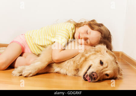 Sleeping little girl lying on her Golden Retriever Stock Photo