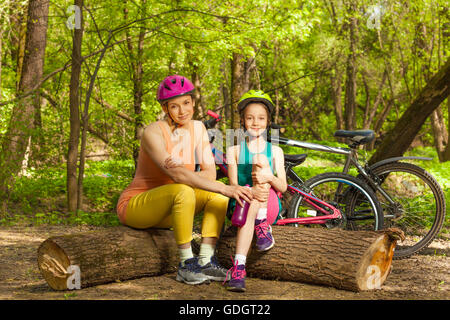 Cute girl and her mom having rest on logs Stock Photo