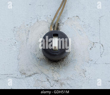Old vintage black switch on a white wall outdoors Stock Photo