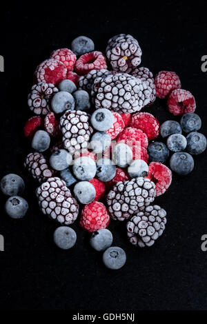 forest fruits frozen, raspberries, blueberries and blackberries on a black stone table