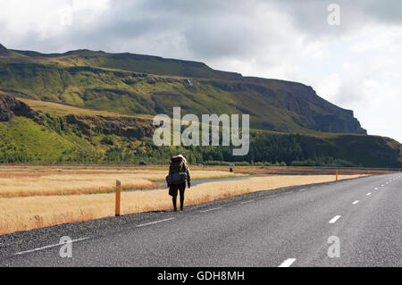 Iceland, Europe: a girl walking on the Route 1, the famous Ring Road that runs around the island, in the area of the waterfall Seljalandsfoss Stock Photo